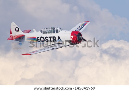 PRETORIA, SOUTH AFRICA -11 MAY 2013 - An Eqstra Harvard trainer with smoke in a cloudy sky during the Time Aviation SAAF Museum Airshow on 11 May 2013 at Swartkop Airforce Base