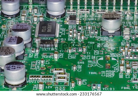 A green PCB with surface mounted chips and silo like capacitors