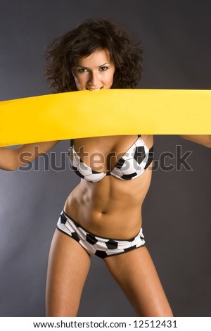 Beautiful girl in fashion lingerie holding yellow banner isolated in studio