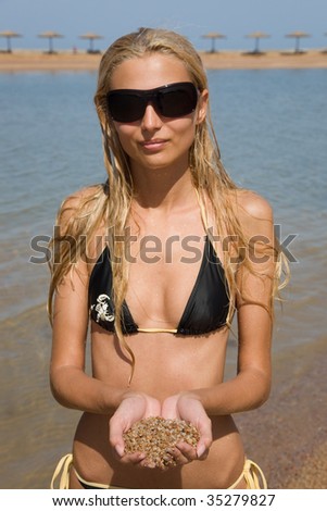 Girl with glasses on a coastline holding sand, closeup outdoor shot