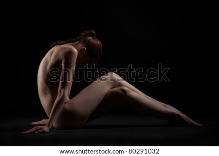 Graceful sitting nude girl over dark background
