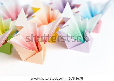 A group of colorful origami birds facing the same direction, on a white background. High key and shallow depth of field.