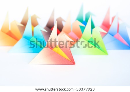 A group of colorful origami birds facing the same direction, on a white background. Shallow depth of field.