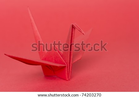 A red paper bird on a red background, shallow depth of field