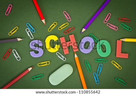 letters with pencils, paper clips, by an eraser on green