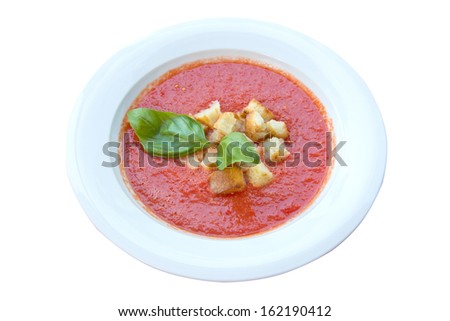 fresh tomato soup, with a basil above in a white dish