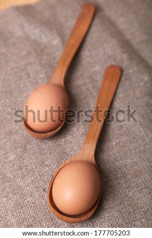 few eggs, in woodden spoons on fabric