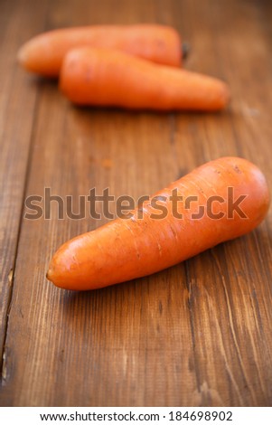 three fresh raw carrots on wooden background