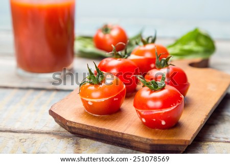 stuffed tomatoes with cheese,fresh basil,juice in plate on wooden background