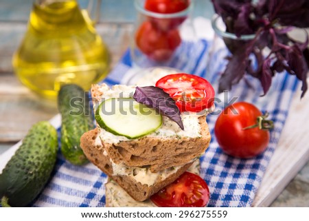 fresh sandwich with tomatoes and cucumber on wooden plate in studio