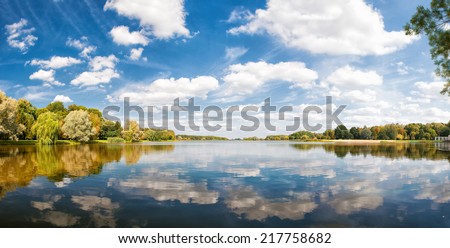 autumn park, trees and blue sky reflected in water, sunny day