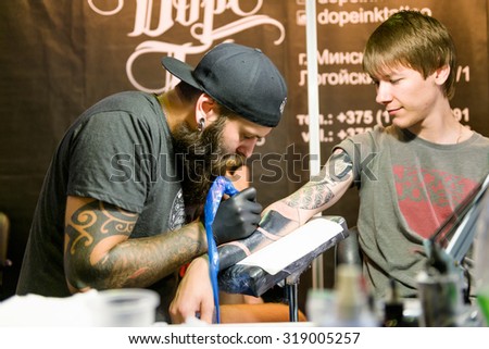 MINSK, BELARUS - SEPTEMBER 19, 2015: Professional tattoo artist doing tattoo on client hand. The 2th International Tattoo Convention