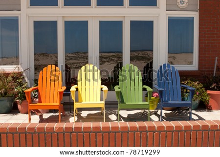 Four colored beach chairs in front of a window reflecting the beach / Colored Beach Chairs
