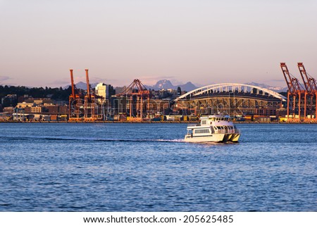 Passenger boat catamaran with several decks and cabins in the bay on the Pacific coast on the background of an industrial zone in the Port of Seattle
