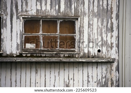 Old window of old wooden building boards chipped and peeling painted white from old paint. Window with a window sill on the wall - a look into the past is impossible.