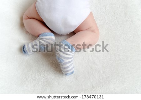 newborn baby sleeping on white. rear view. butt in a diaper, with a adorable crossed legs and feet