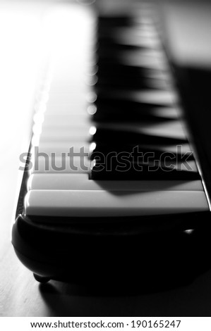 B&W shot of a small piano keyboard, dramatic lighting and contrast, selective focus