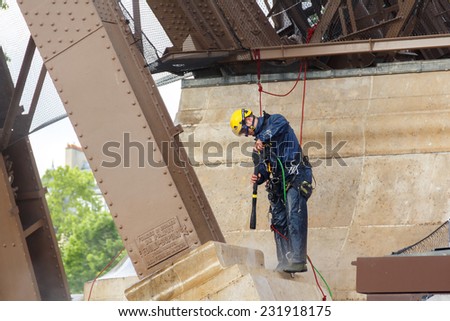 Paris, France - May 9, 2014: Man steeplejack washes foundation of the Eiffel Tower.