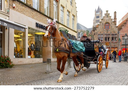 Bruges, Belgium - December 26, 2014: Horse-drawn carriage on the ancient streets of Bruges. Popular activities among tourists.