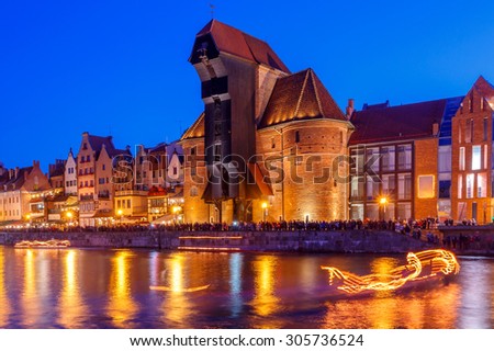 Multi-colored facades and boat on the central waterfront in Gdansk at night.