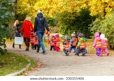 Tallinn, Estonia - October 19, 2015: A kindergarten teacher with small children dressed in reflective safety vests for a walk in the park in Tallinn.