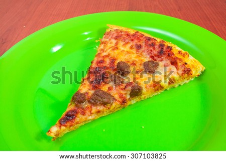 Slice of pizza on round green dish