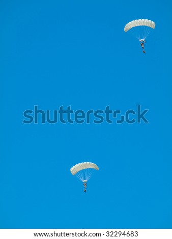 Group of white parachute jumpers  against pure blue sky