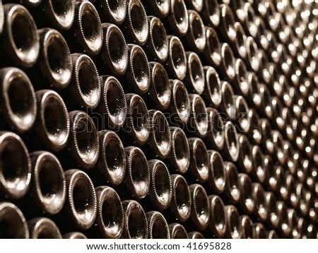 Row of Bordeaux wine bottles stacked in a cellar with shallow depth of field