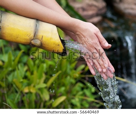 Asian woman cleaning her hands in a pure water stream