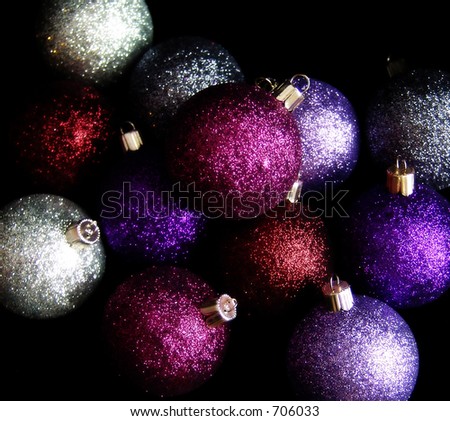 Pile of glitter Christmas ornaments on black background.