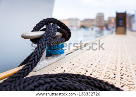 A white yacht moored with a line tied around a fixing on the quayside/ Mooring at a pier