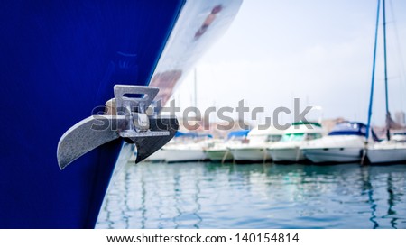 The anchor on the bow of a ship on a harbor with other boats on the background/ Anchor on ship in harbor