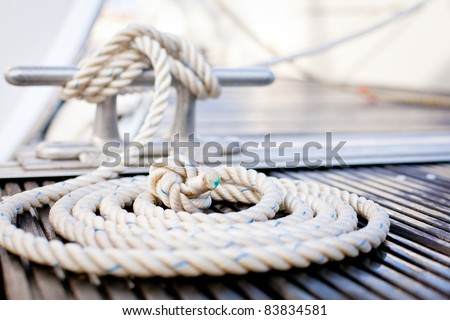 Close-up of a mooring rope with a knotted end tied around a cleat on a wooden pier/ Nautical mooring rope - stock photo