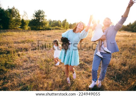 Happy family: young father with his little children walking in the field in summer morning.