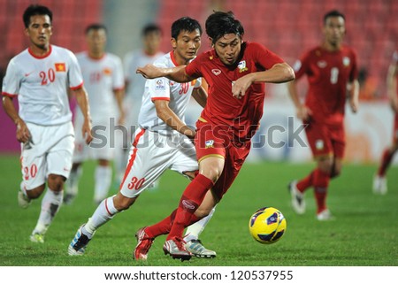 BANGKOK THAILAND-NOVEMBER 30:Kirati Keawsombut of Thailand (red) runs with the ball during the AFF Suzuki Cup between Vietnam and Thailand at Rajamangala stadium on Nov30, 2012 in Bangkok,Thailand.