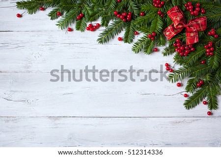 Christmas wooden background with branches of trees, berries and red ribbon