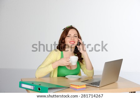 Happy young successful woman working at desk with laptop and mobile phone isolated on white