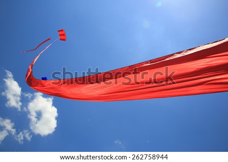 Long red kite against a vivid blue sky.