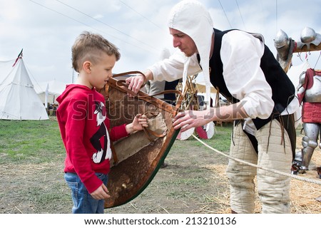 CREVALCORE,ITALY-MAY 4,2013:actors dressed in medieval clothes show to a child how to use a shield during an medieval event