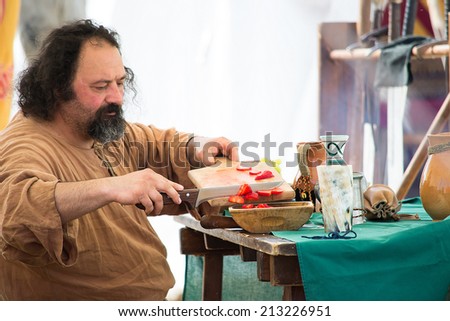 CREVALCORE,ITALY-MAY 4,2013:bearded man dressed in traditional clothing prepares a lunch during medieval reenactment in Italy