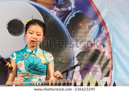 PADOVA,ITALY-DECEMBER 8,2014:An oriental woman with traditional costumes plays the koto during a perform inside an event called Festival of East which takes place in the Italian city of Padua