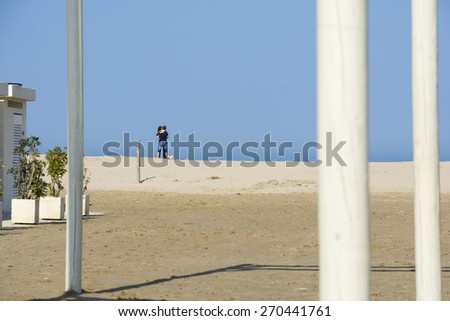 RIMINI,ITALY-APRIL 12,2015:A couple of young guys hugging each on the deserted beach of Rimini in Italy during a sunny day