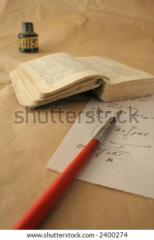 The still life photo of the old book, parchment, crow quill and bottle of the Indian ink