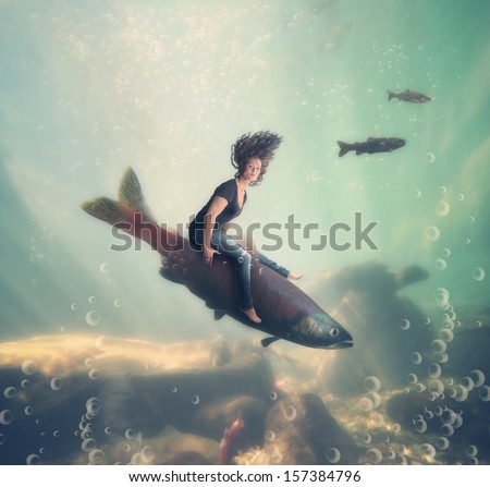 a pretty woman riding a fish under the water of an ocean or sea