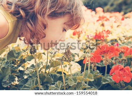 a small girl smelling some flowers vintage toned