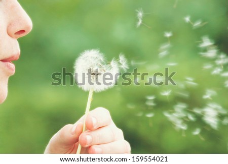 a woman blowing on a dandelion muted colors vintage toned