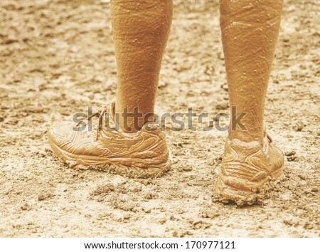 a pair of very muddy shoes and legs