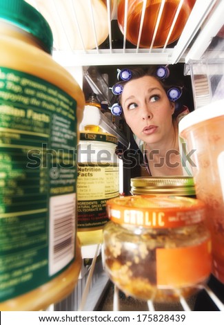 a woman peering into an open fridge