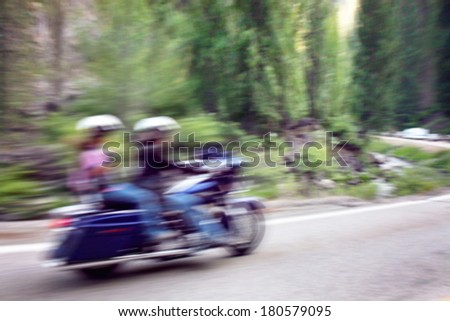 two bikers on mountain highway, riding around a curve with a motion blur