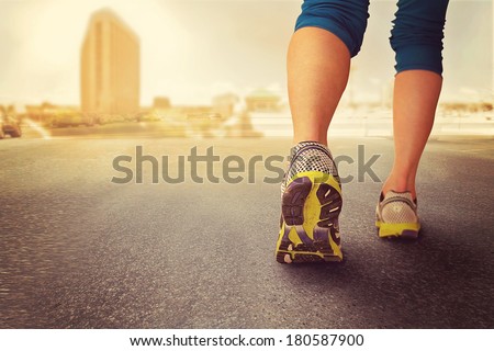 a woman with an athletic pair of legs going for a jog during sunrise or sunset - healthy lifestyle concept done with an instagram like filter  - healthy lifestyle concept  on a cityscape background